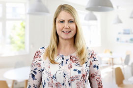 Bewerbungsfotos Hilden. Bewerbungsfoto von einer Frau vor unscharfem Büro Hintergrund.