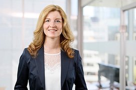 Bewerbungsfotos Hilden. Entspanntes Bewerbungsfoto von einer Frau vor unscharfem Büro Hintergrund.