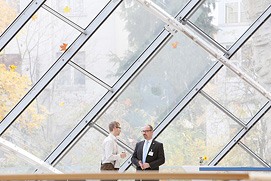 Zwei Personen stehen vor einer riesigen Glasfassade bei einem Frankfurter Business Event. Besondere Momente festgehalten  im Eventfoto für Frankfurt.