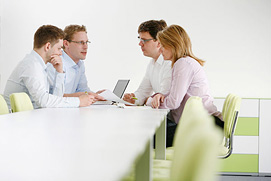 Businessfotografie einer Kommunikationssituation am Tisch. Mitarbeiter bei der Besprechung. Positives Unternehmensbild für ein Kölner Unternehmen.
