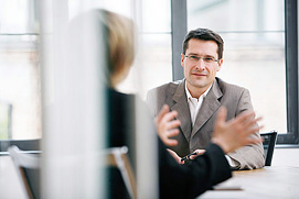 Beratungssituation mit Zwei Personen am Tisch. Die interessante Perspektive macht das Businessfoto zu einem Hingucker. Das Foto wurde für einen Businesscoach aus Köln erstellt