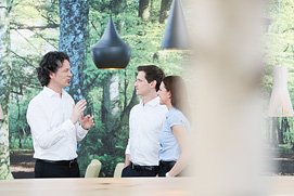 Ein Businessfoto der Büroatmosphäre in einem Bonner Unternehmen. Hand, Stift, und Tastatur ergeben ein stimmiges Gesamtbild.