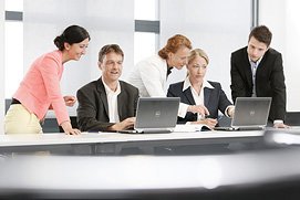 Ein Businessfoto der Büroatmosphäre in einem Kölner Unternehmen. Hand, Stift, und Tastatur ergeben ein stimmiges Gesamtbild.
