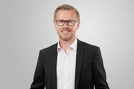 Mitarbeiterfotos Dortmund. Dynamisches Mitarbeiterportrait von einem Mann vor grauem Hintergrund für ein Unternehmen.