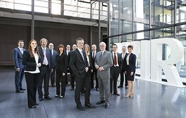 Entspanntes Teamfoto einer größeren Gruppe in einer Eingangshalle für ein Unternehmen aus Köln.