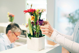 Atmosphärisches Praxisfoto einer Praxisgehilfin die einen Blumenstrauss richtet. Professionelle Praxisfotos in Düsseldorf.