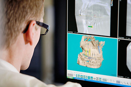 Ein Zahnarzt betrachtet 3D Implantate als Simulation auf dem Monitor. Zahnarztpraxis Fotos für Köln.