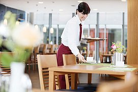 Eine Mitarbeiterin deckt einen Tisch ein in einem Hotel Restaurant in Essen. Authentische Hotel und Restaurant Fotos in Essen und NRW.
