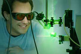 Zentralperspektivische Industrieforografie mitarbeiter vor grünem Laser.