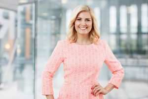 Business Portraits, Köln, Bonn, Leverkusen, Essen. Frau lächelnd vor Business Hintergrund.