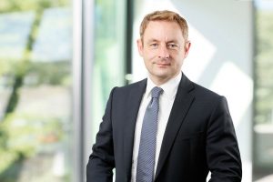 Business Portrait Köln, Düsseldorf, Bonn, Leverkusen, Essen. Geschäftsführer lächelnd vor Business Hintergrund.