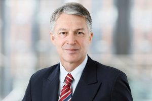 Business Portrait Köln, Düsseldorf, Bonn, Leverkusen, Essen. Manager lächelnd vor Business Hintergrund.