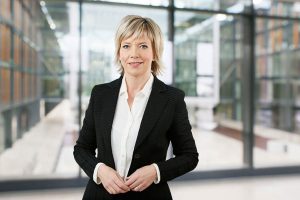 Business Portraits Düsseldorf, Köln, Bonn, Leverkusen, Essen. Frau lächelnd vor Business Hintergrund.