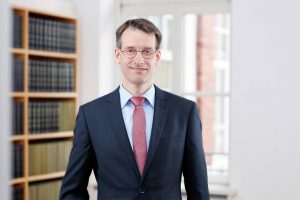 Business Portrait Köln, Düsseldorf, Bonn, Leverkusen, Essen. Rechtsanwalt lächelnd vor Business Hintergrund.