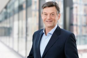 Business Portrait Köln,, Bonn, Leverkusen, Essen. Mitarbeiter lächelnd vor Business Hintergrund.