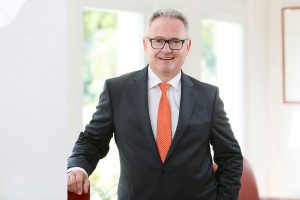 Business Portrait Köln, Düsseldorf, Bonn, Leverkusen, Essen. Geschäftsführer lächelnd vor Business Hintergrund.