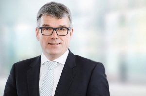 Business Portraits Düsseldorf, Köln, Bonn, Leverkusen, Essen. Geschäftsführer lächelnd vor Business Hintergrund.