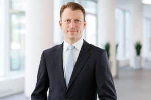 Business Portraits Düsseldorf, Köln, Bonn, Leverkusen, Essen. Anwalt lächelnd vor Business Hintergrund.