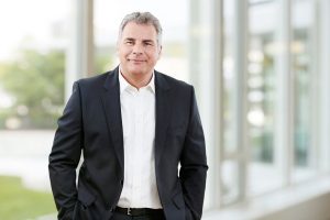 Business Portrait Köln, Düsseldorf, Bonn, Leverkusen, Essen. Geschäftsführer lächelnd vor Business Hintergrund.