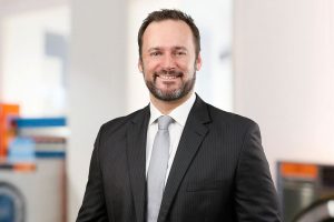 Mitarbeiterportrait Mann, lächelnd, vor Business Hintergrund, Köln, Bonn, Düsseldorf, Essen, Leverkusen, NRW